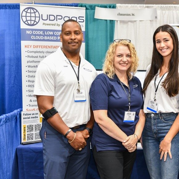 Booth Two men and two women posing for a photo in front of a booth during an expo event