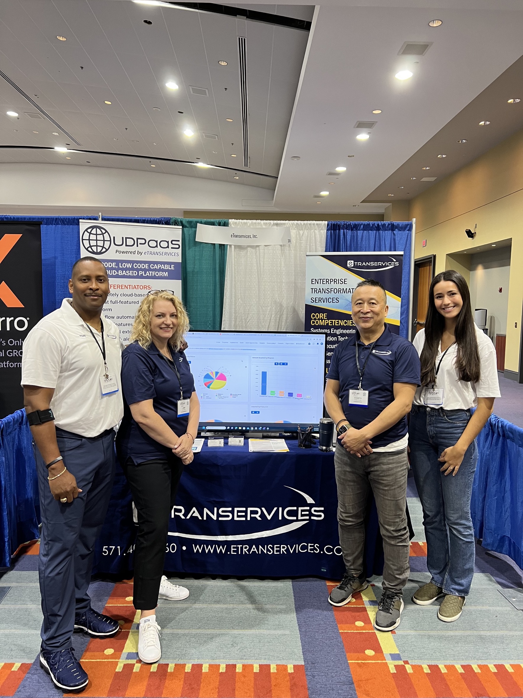 Two men and two women posing together in front of a booth